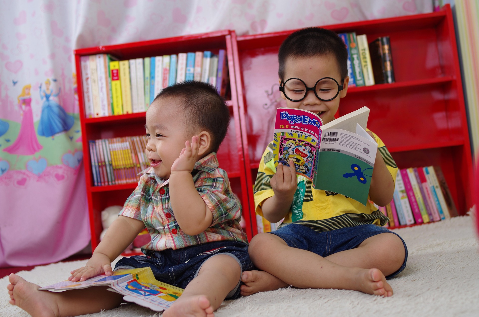 Two brothers are looking at kid books and laughing.