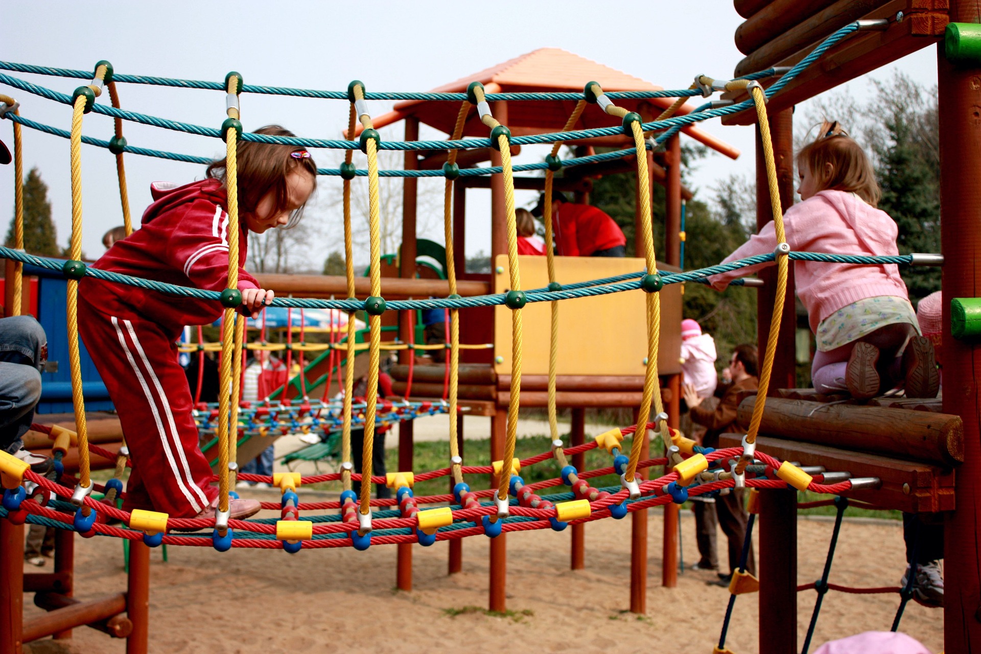 Two young girls explore different parts of the play equipment