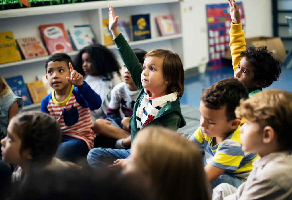A group of children raise their hands to answer a question