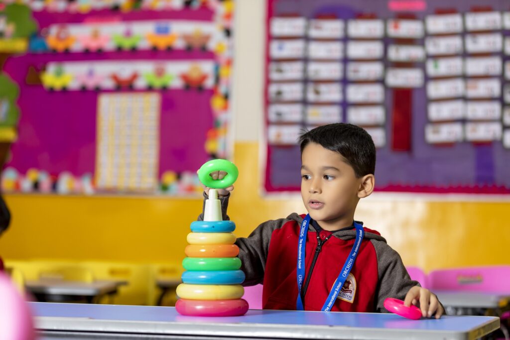 A young boy puts the final ring on a stacking toy