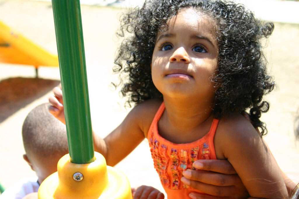 A young girl climbing play equipment outside