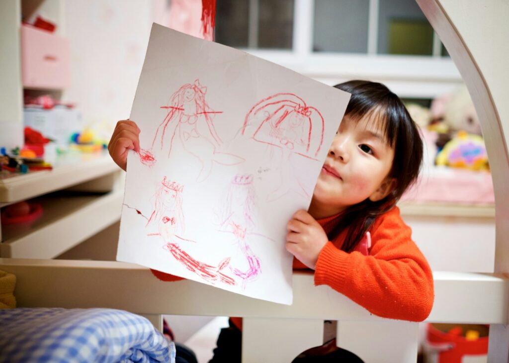 A young girl shows her colorful drawing
