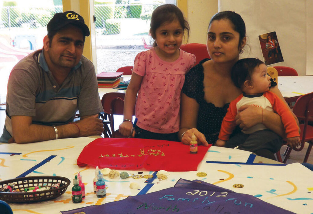 A young family sits around a table doing a creative activity together