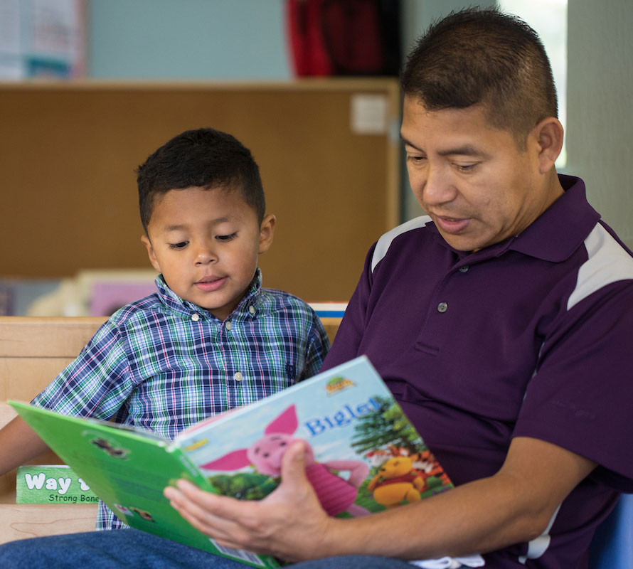 A father reads a story book to his young son